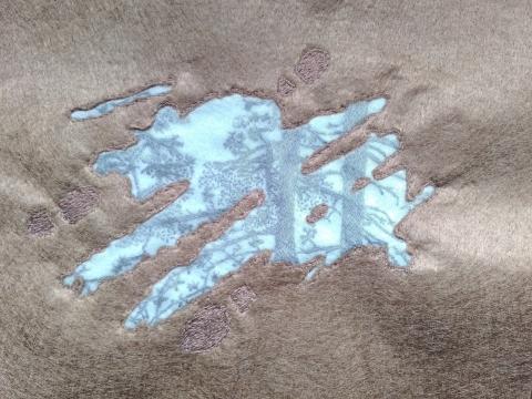 A reflection of trees can be seen in the surface of a puddle. Around the muddy puddle are footprints.