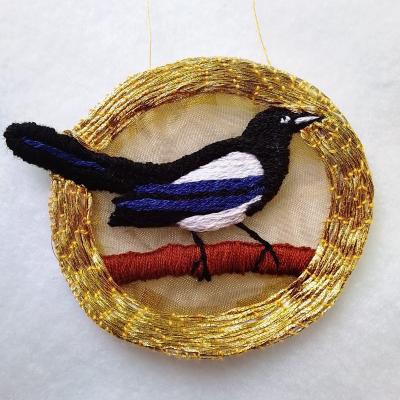 An embroidered magpie in a gold circle