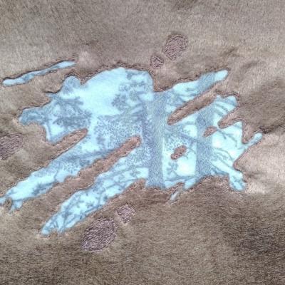 A reflection of trees can be seen in the surface of a puddle. Around the muddy puddle are footprints.