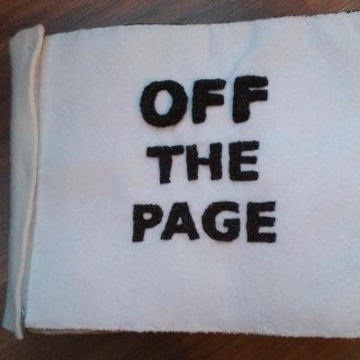 A white cover with black block capitals made from stuffed needlelace that raises all the letters high off the background.