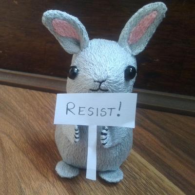A light-grey stylised rabbit holds up a paper sign saying "RESIST!"